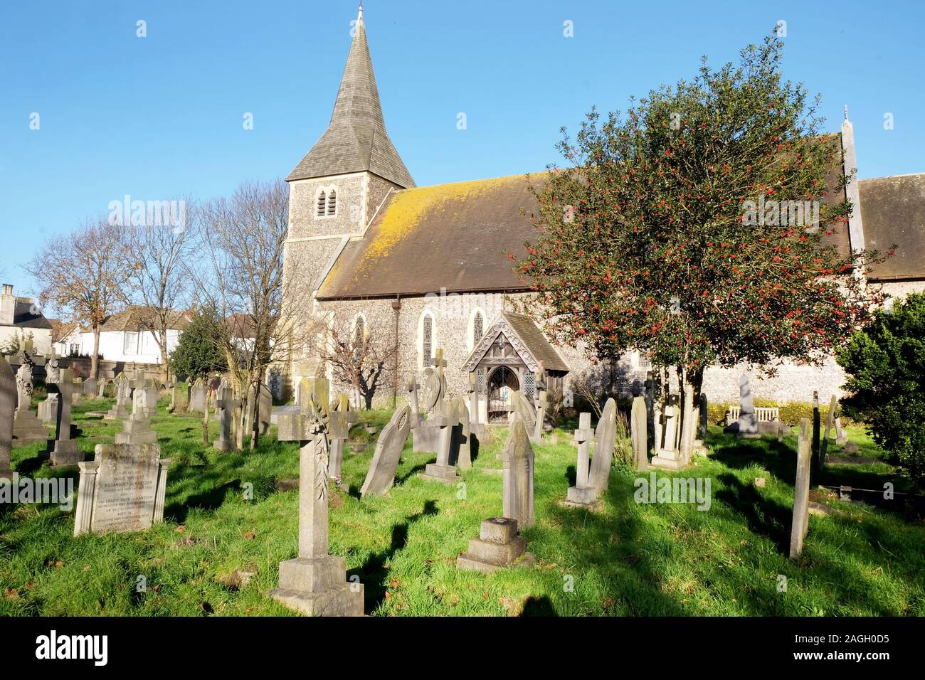 A beautiful old church and grave yard with a holly tree full of red berries in Hove, Brighton, East Sussex, united kingdom, the grave tombs are in the Stock Photo