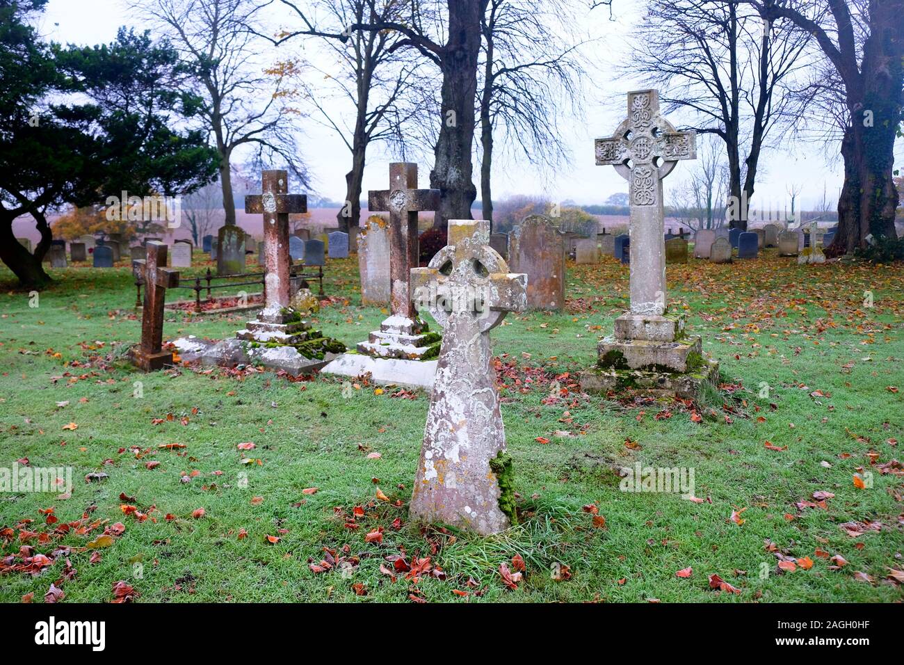 An eary scarey English grave yard with about fifty grave stones, the headstones in the foreground are in the shape of large Cristian crosses, two larg Stock Photo