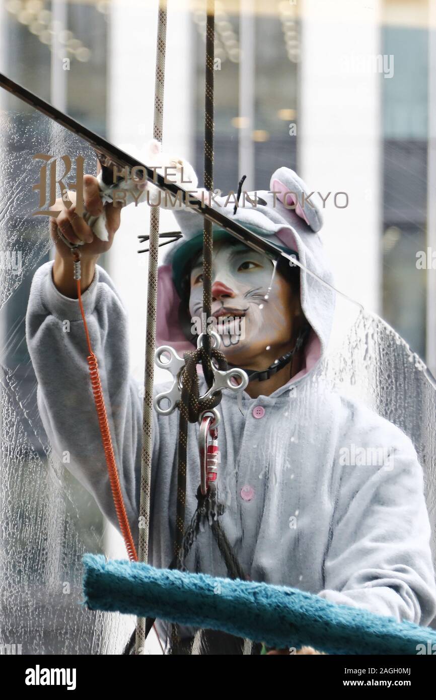 Tokyo, Japan. 19th Dec, 2019. A window cleaner dressed as a mouse wipes ...