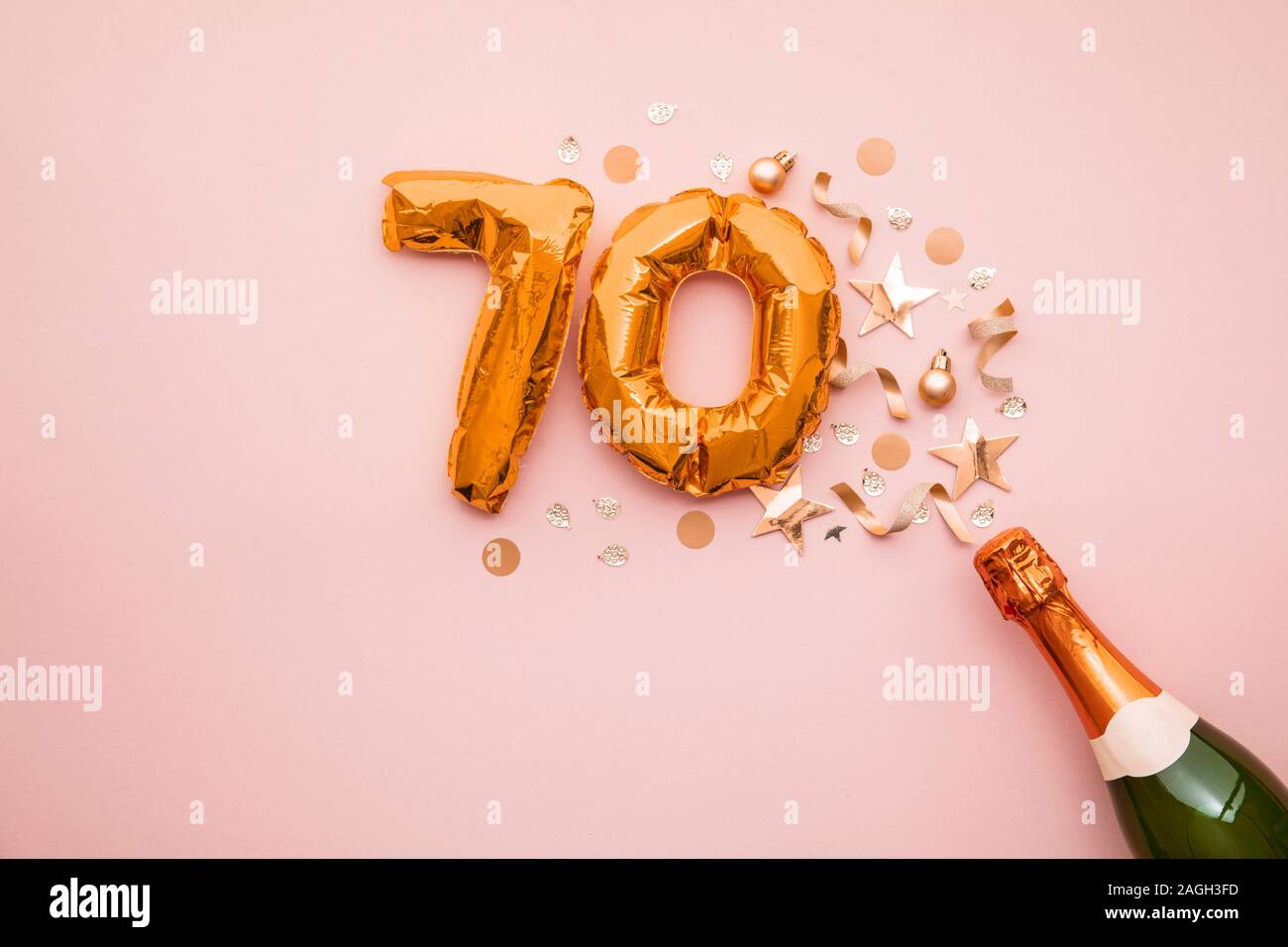 Happy 70th anniversary party. Champagne bottle with gold number balloon. Stock Photo