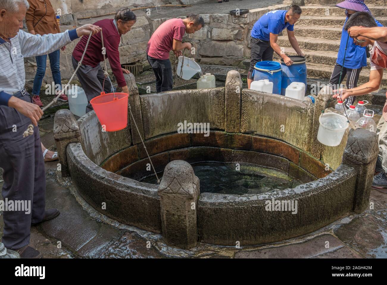 Local residents fetch water from Daban Well, dubbed as the 'first well in south Yunnan', in Jianshui, Honghe, Yunnan, China. Stock Photo