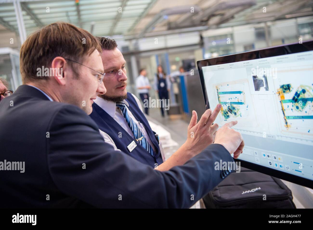 Munich, Germany. 19th Dec, 2019. Hans Reichhart (l;CSU), Minister of Transport of Bavaria, taps on the touch screen of a baggage control station at Munich Airport. Transportation Minister Reichhart, (CSU) announced the first test results of the newly installed safety system in a press conference. Credit: Lino Mirgeler/dpa/Alamy Live News Stock Photo