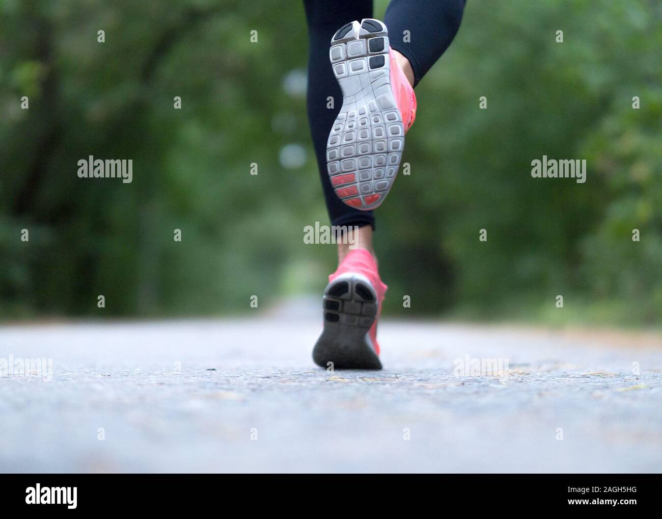 Feet of a runner. Woman runs in the forest. Close-up of sneakers. Helathy lifestyle. Stock Photo