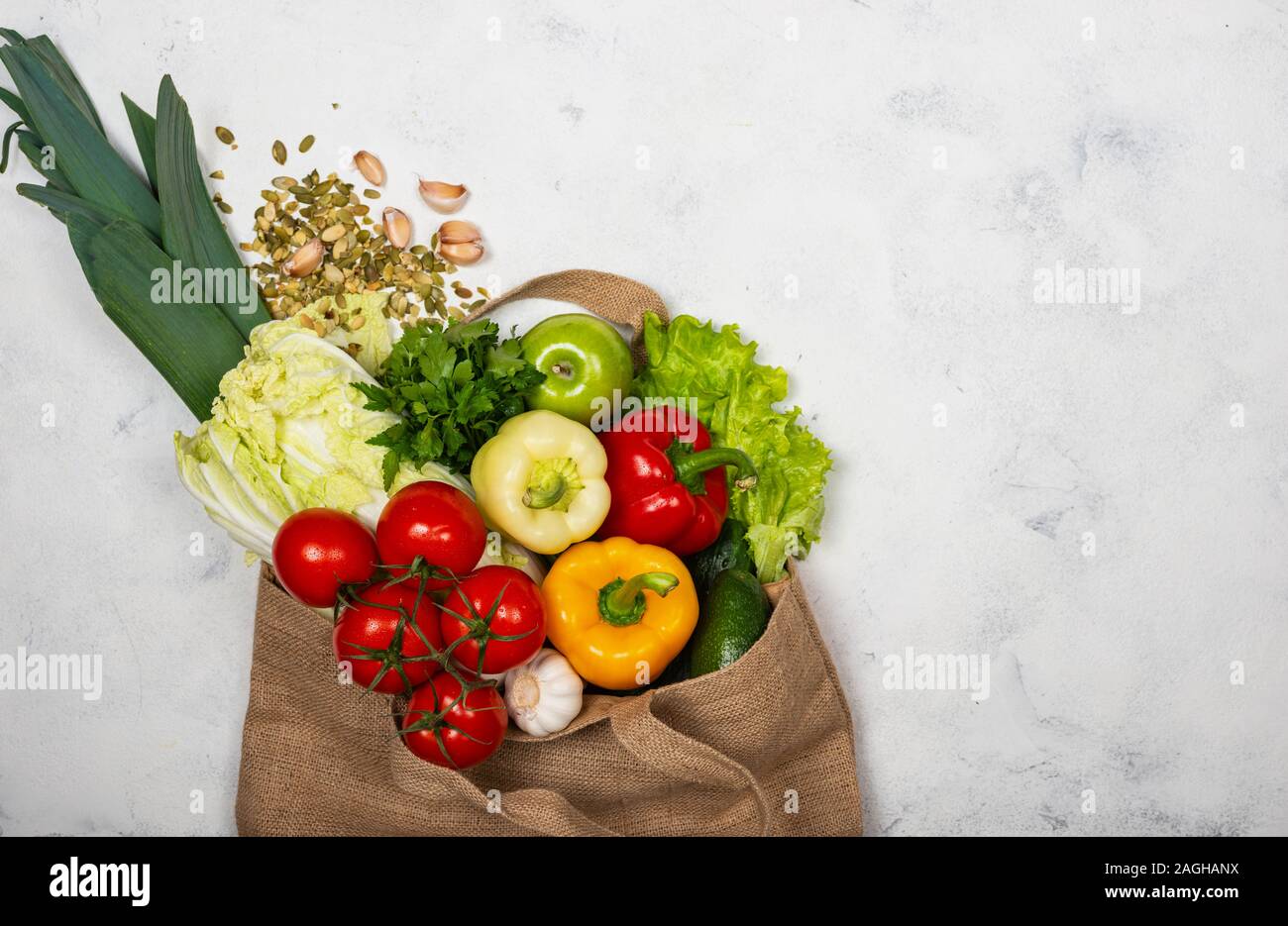 Eco-friendly fabric bag full of fresh vegetables on a light background ...
