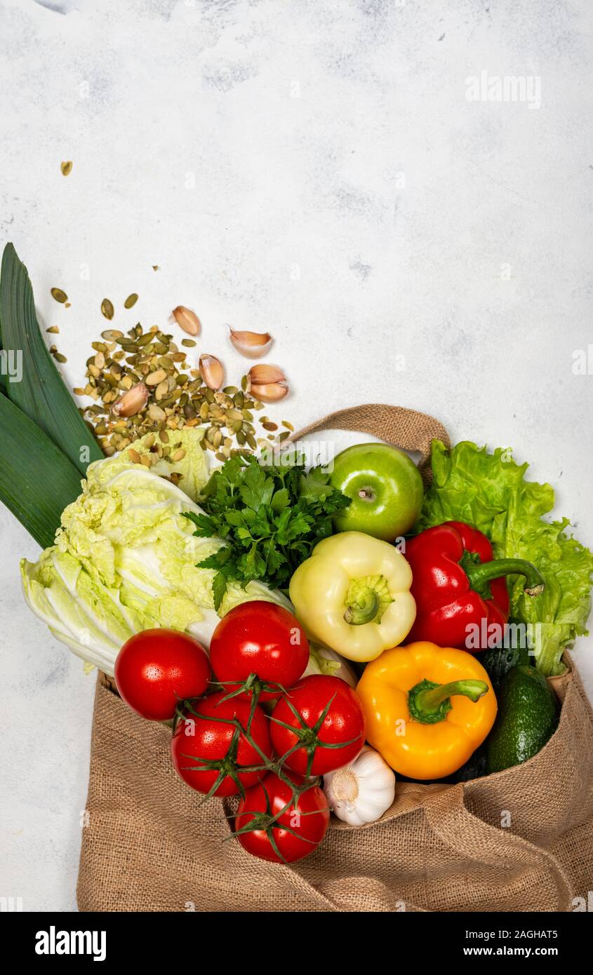 Eco-friendly fabric bag full of fresh vegetables on a light background ...