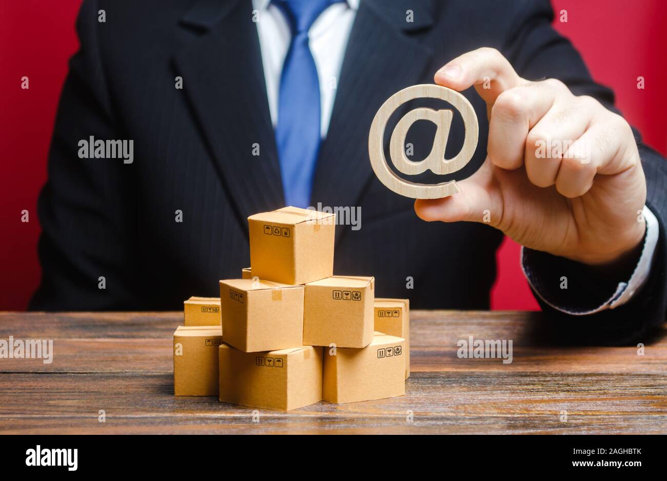 Businessman holds an email internet symbol over boxes. Sales and distribution of goods and products through online. Advertising and marketing, sale. S Stock Photo