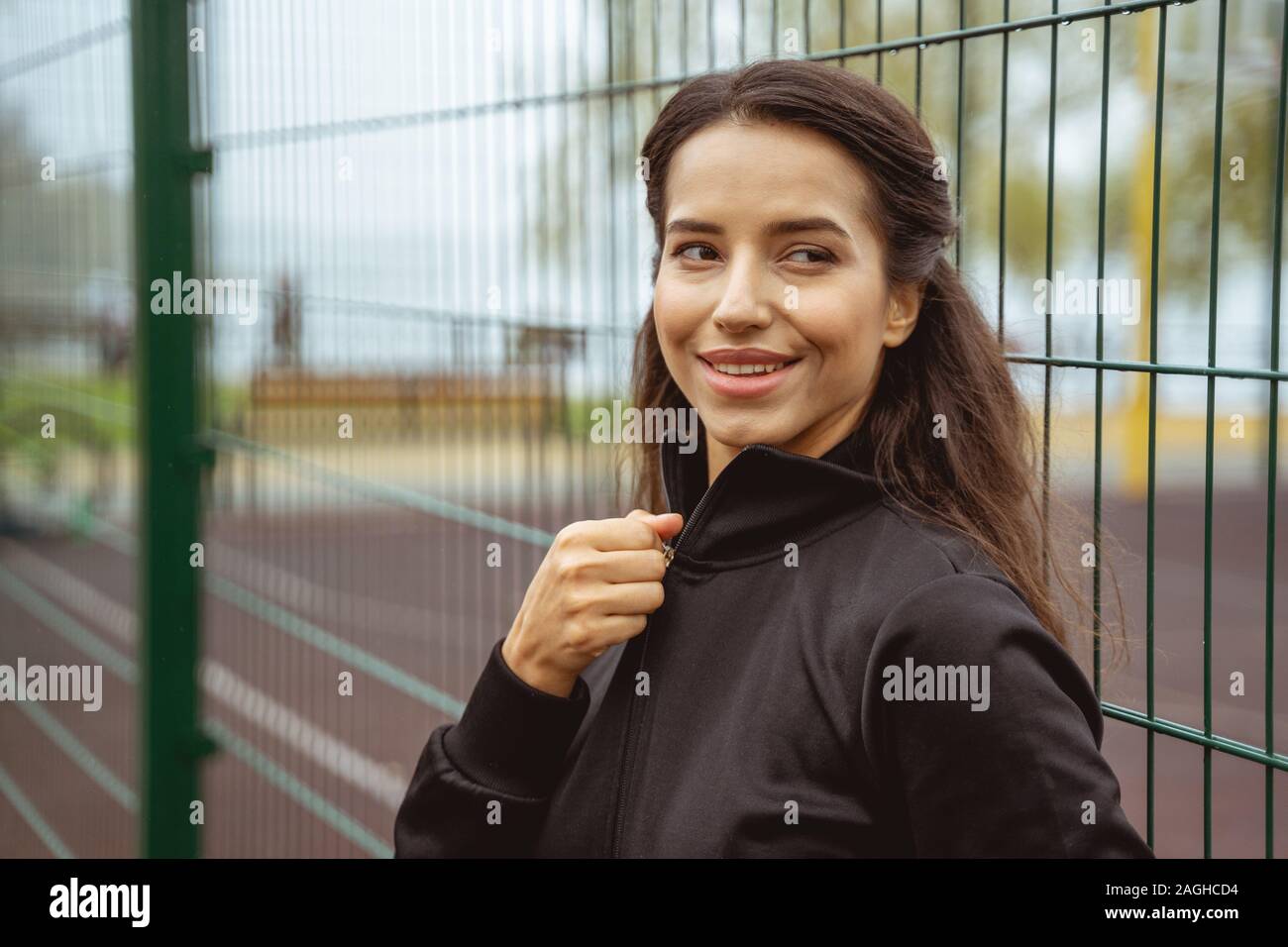 Positive delighted brunette girl wearing tracksuit jacket Stock Photo