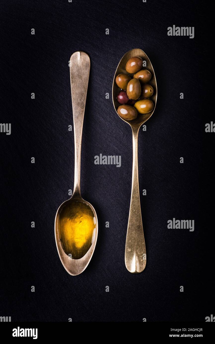 On The Slate Stone Two Tablespoons One Full Of Extra Virgin Olive Oil And The Other With Olives Stock Photo Alamy