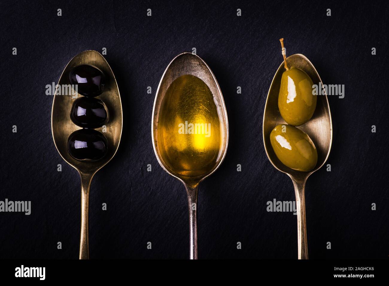 On The Slate Stone Three Tablespoons One Full Of Extra Virgin Olive Oil And The Others With Green And Black Olives Stock Photo Alamy
