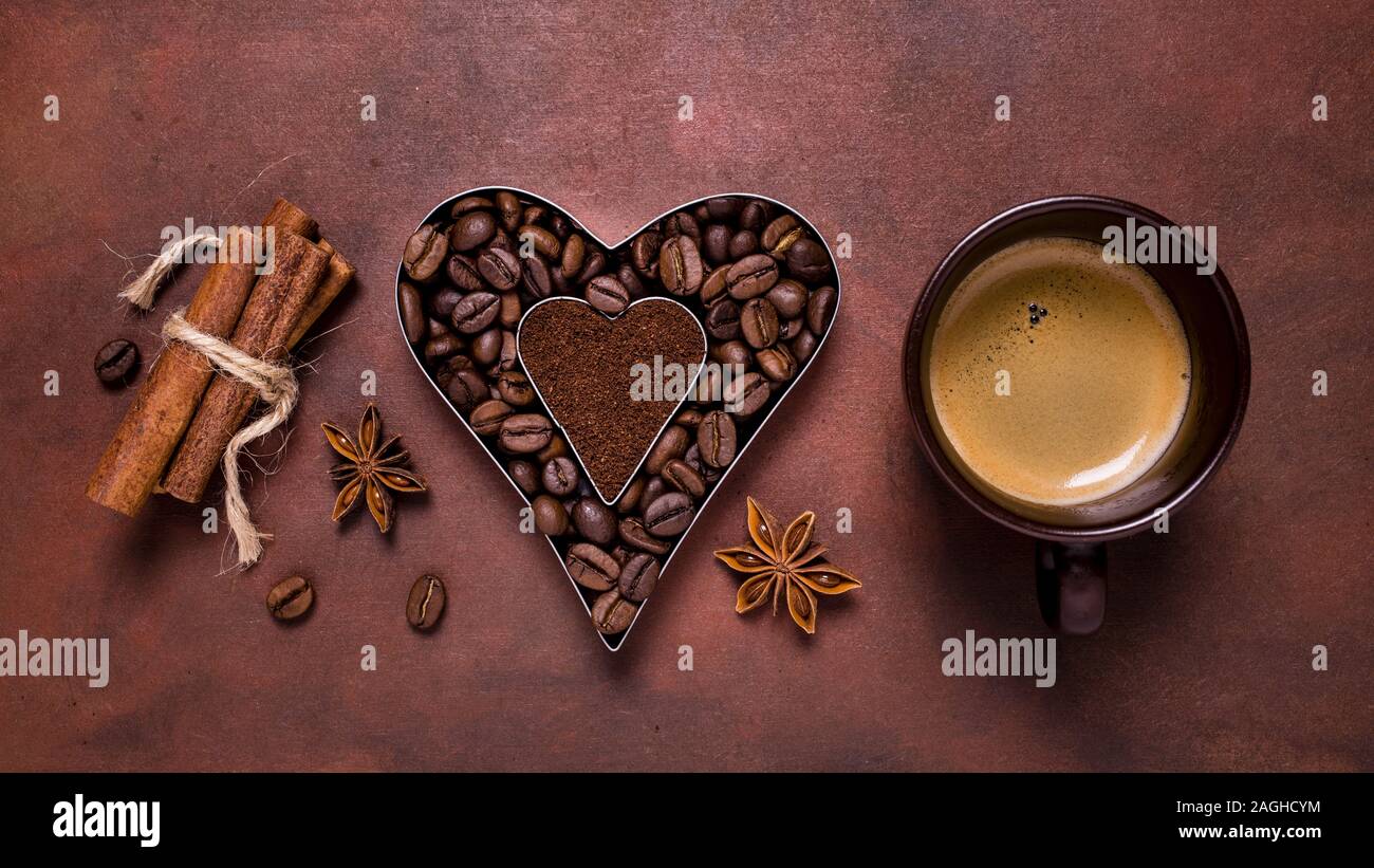 composition with a cup of espresso, and heart-shaped silhouette with coffee beans and ground coffee Stock Photo