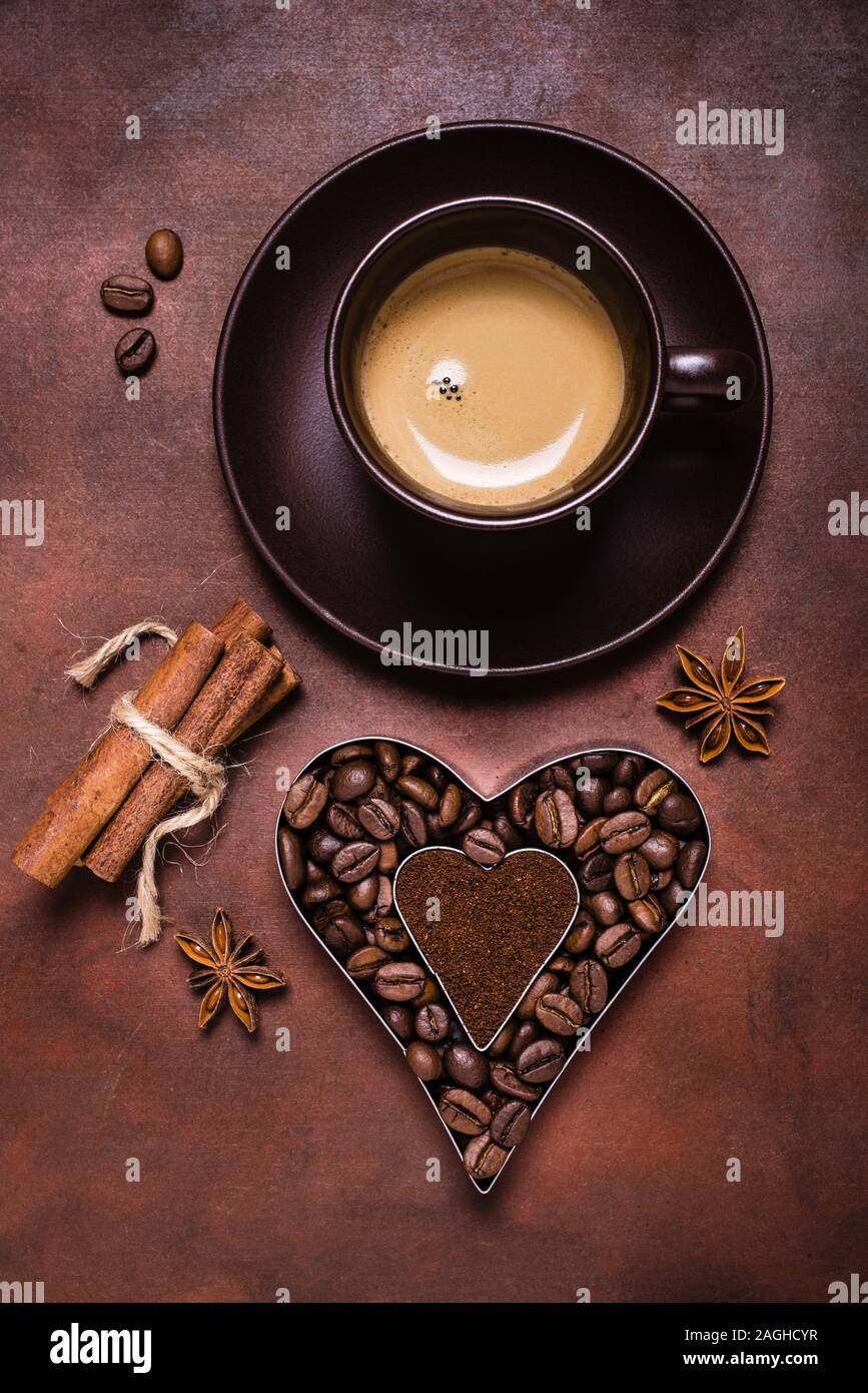 composition with a cup of espresso, and heart-shaped silhouette with coffee beans and ground coffee Stock Photo