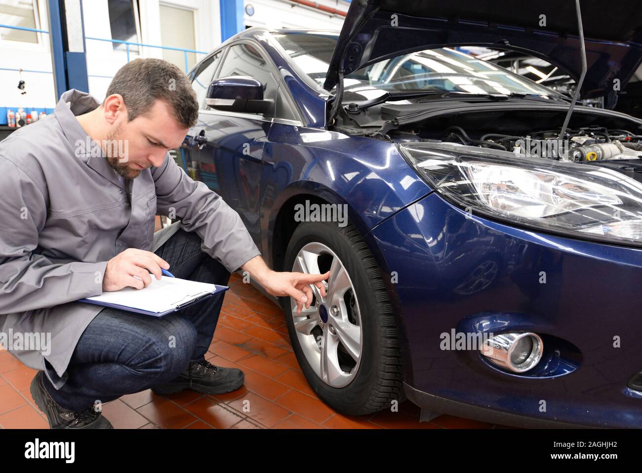 mechanic in a workshop checks and inspects a vehicle for defects Stock Photo