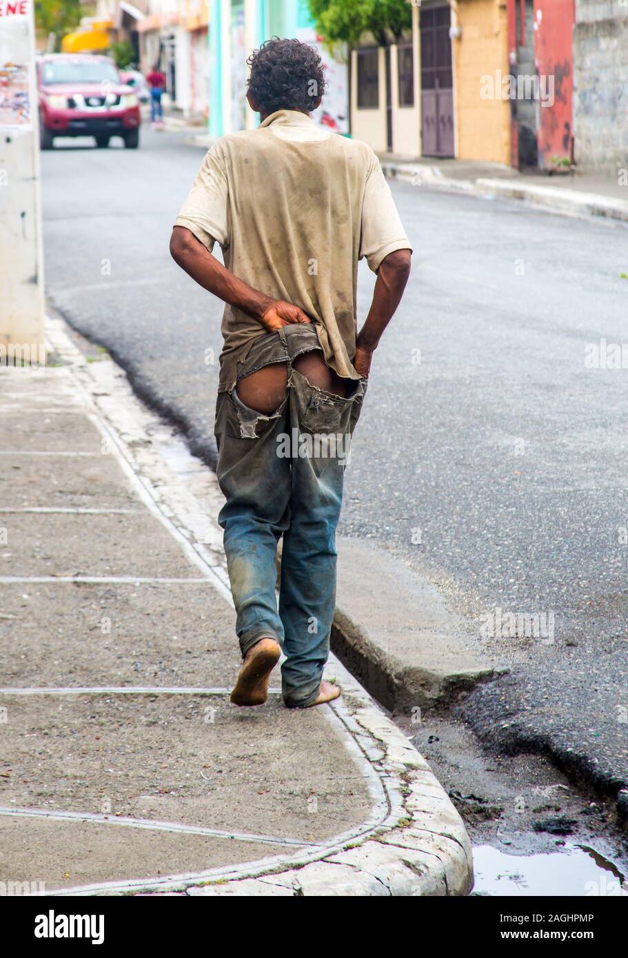 dramatic image of a poverty stricken dominican man walking down the street  with his pants falling apart barefoot Stock Photo - Alamy