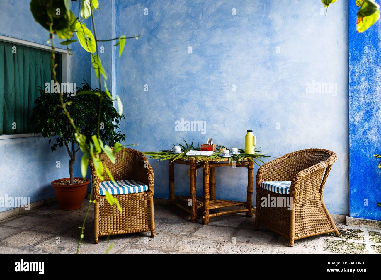 cozy sitting area in the shade with two rattan chairs, a table is set for tea Stock Photo