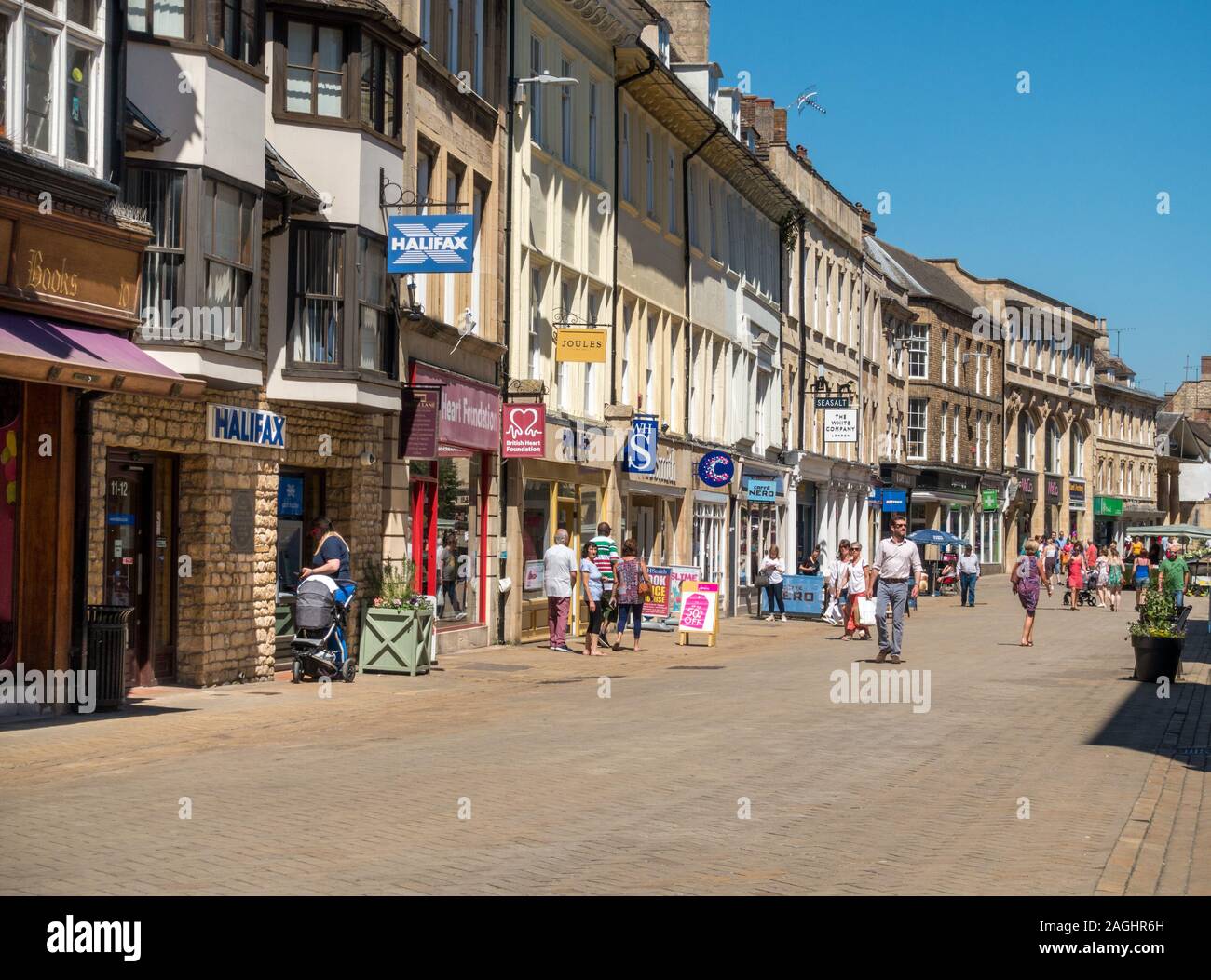 Shoppers and long row of traditional shop fronts in pedestrianised High Street on a sunny summer day, Stamford, Lincolnshire, England, UK Stock Photo