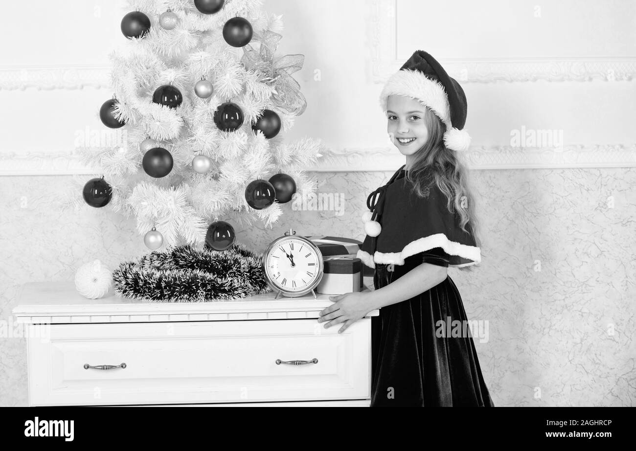 Last minute till midnight. New year countdown. Last minute new years eve plans that are actually lot of fun. Girl kid santa hat costume with clock cou Stock Photo