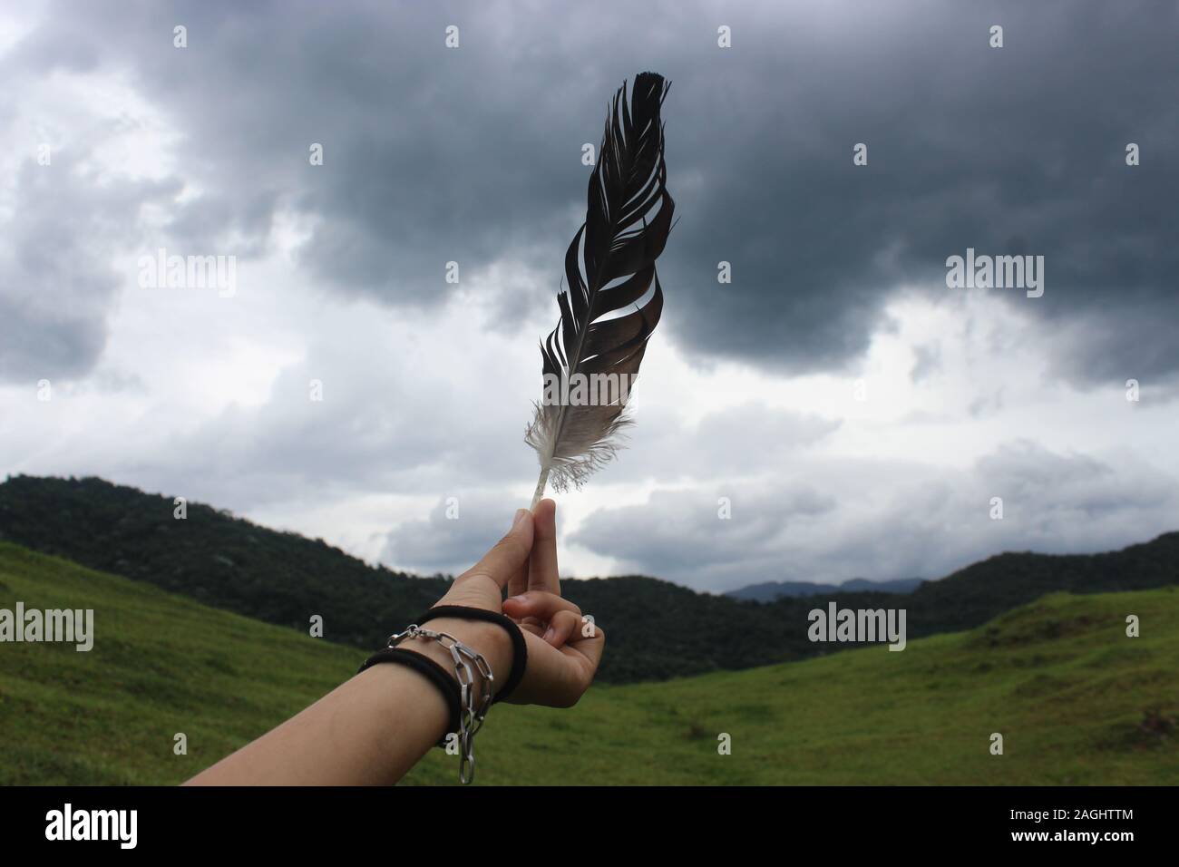 mao segurando uma pena,ao ceu,em uma montanha Stock Photo