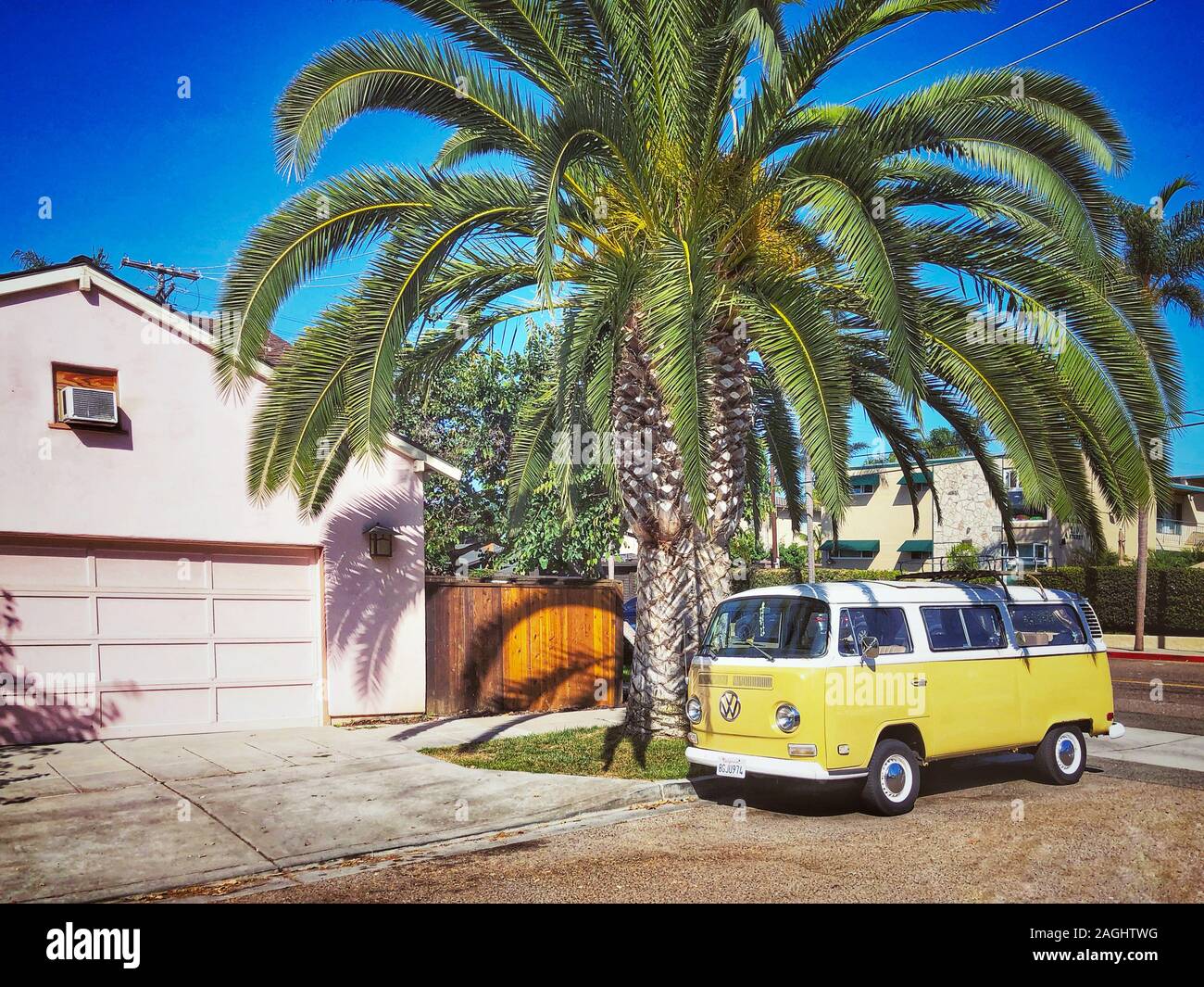 Classic beige and white vintage Volkswagen T1 camper van parked in front of pink house. San Diego, California, USA. July 13th, 2019 Stock Photo