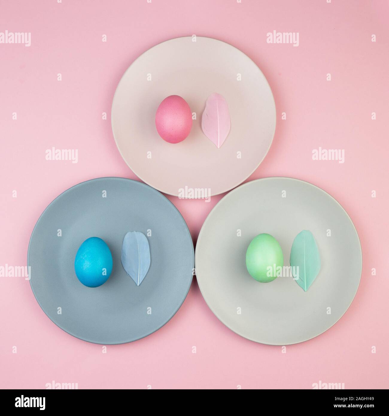 Easter multi-colored eggs and feathers on pink background. Stock Photo