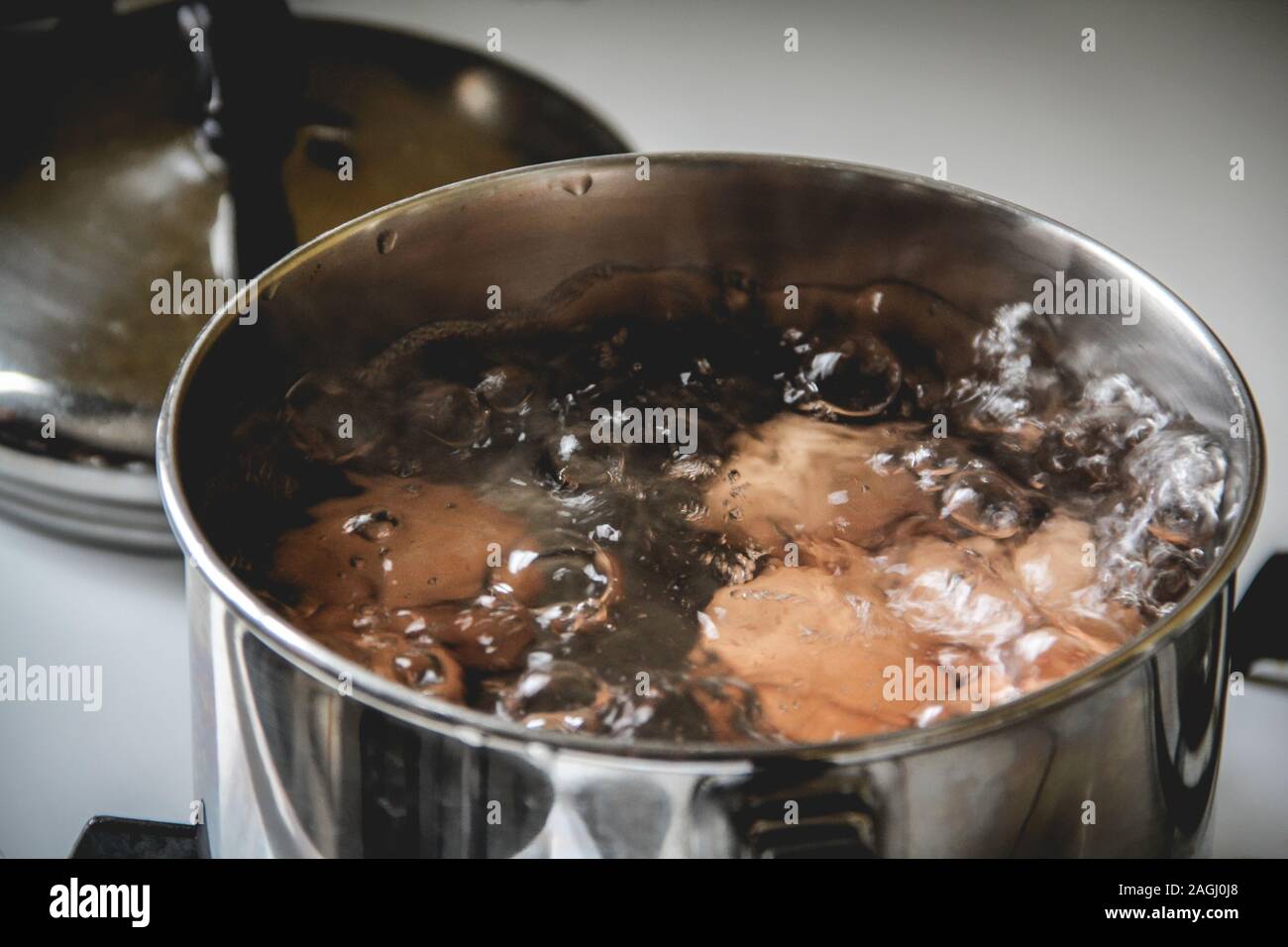 Brown eggs boiling in a small pot on the stove Stock Photo