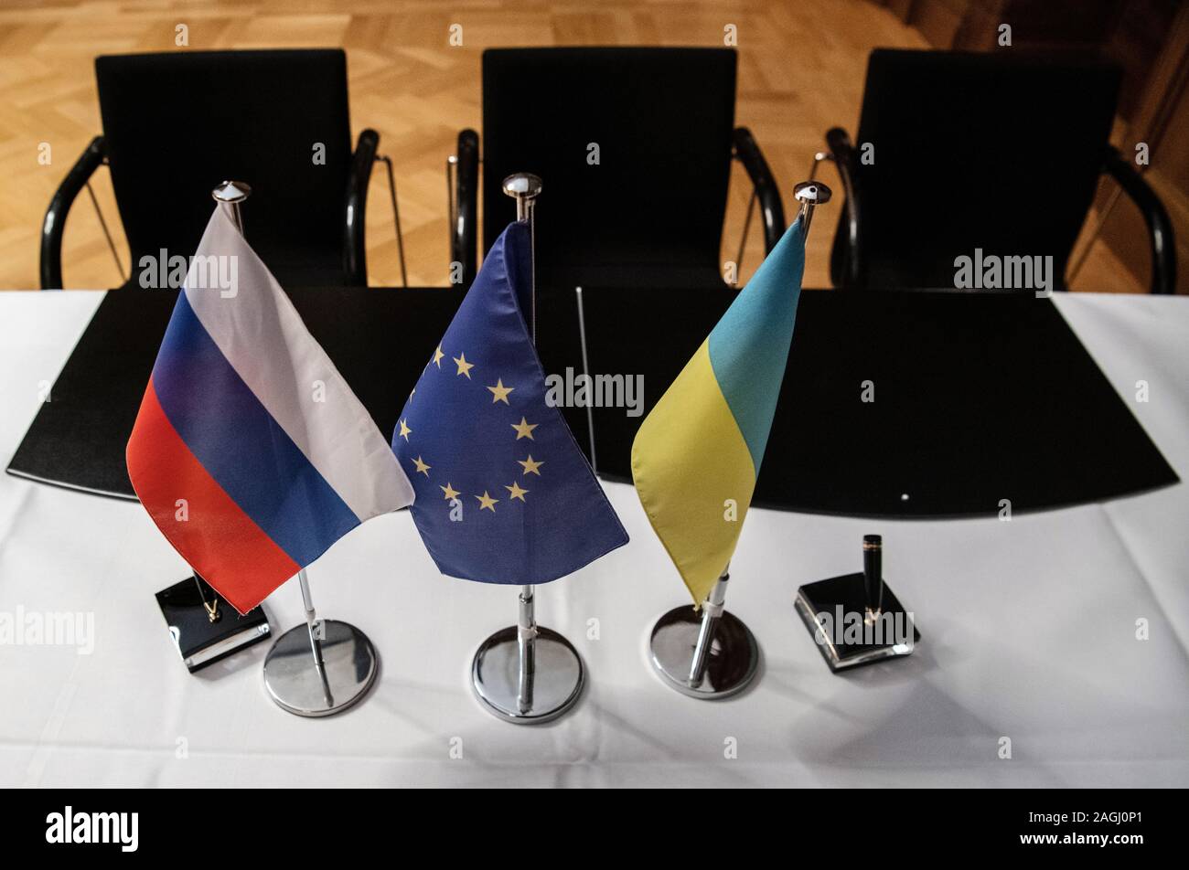 19 December 2019, Berlin: The flags of Russia (l-r), the EU and Ukraine, are on a table in the Ministry of Economy before a press conference after negotiations between Russia and Ukraine mediated by the EU and Germany. Russia and Ukraine have reached an agreement in principle on a new gas transit contract. Photo: Paul Zinken/dpa Stock Photo