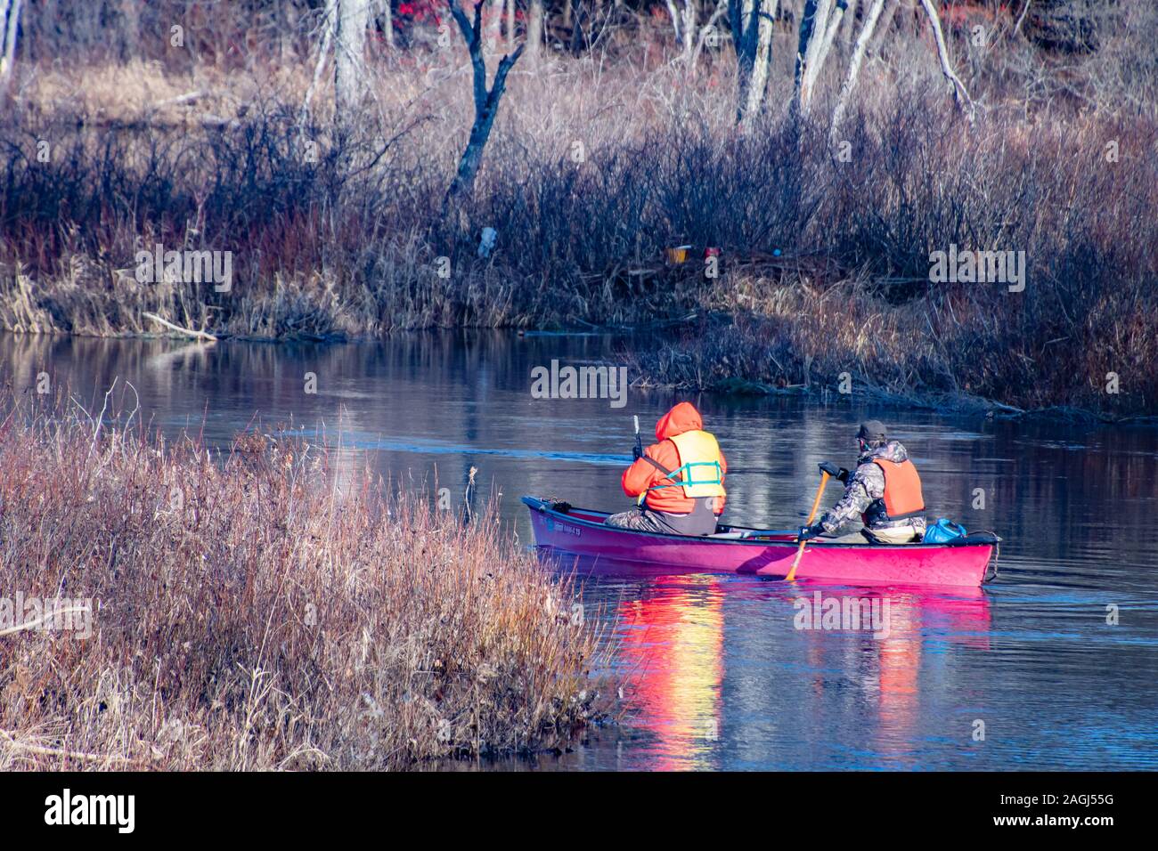 Two male duck hunters paddling a canoe in the Sacandaga River near Speculator, NY USA in the Adirondack Mountains in early winter Stock Photo