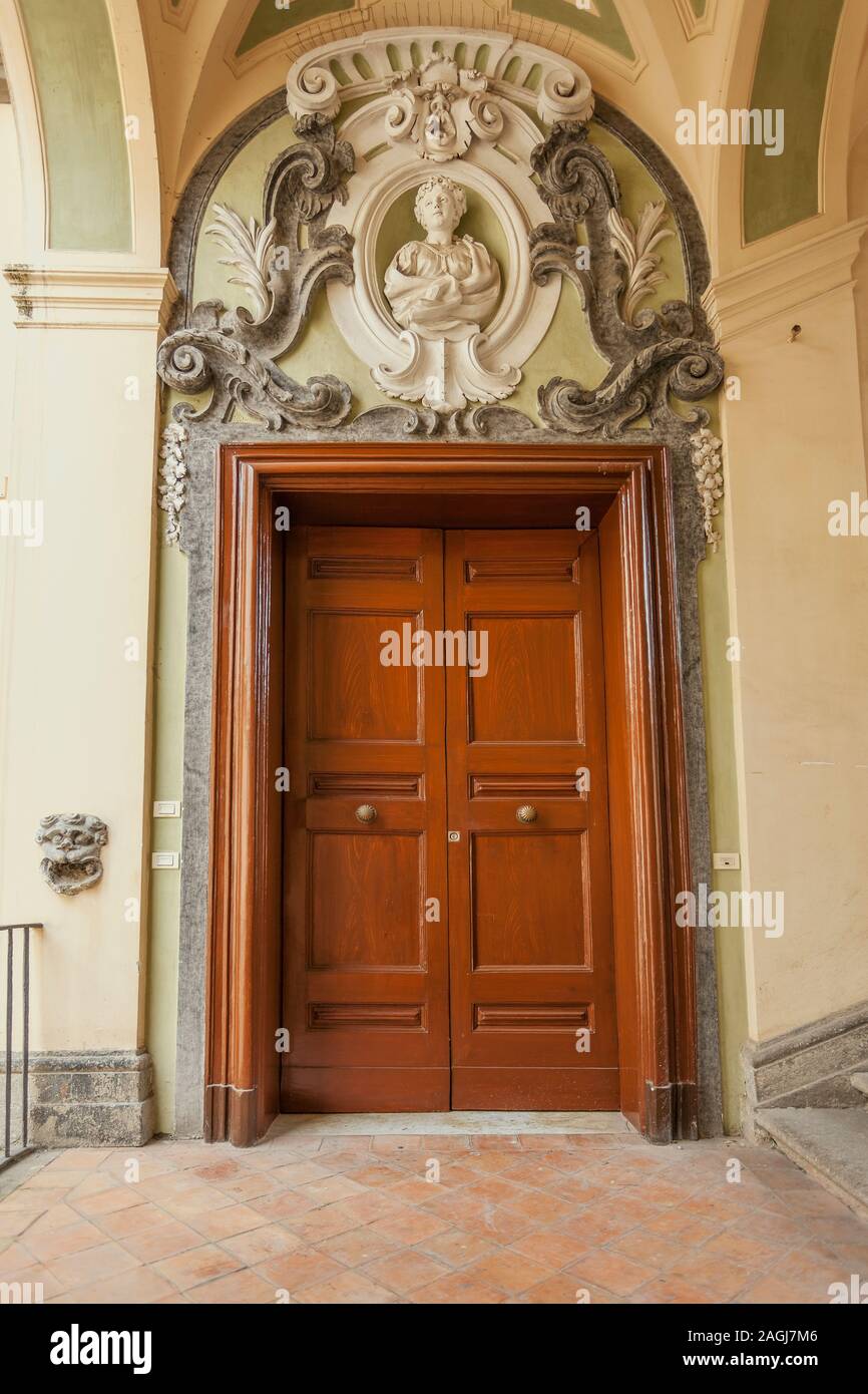 Entrance door decorate with sculpture in the famous double-flight staircase of the Palazzo dello Spagnolo, Naples, designed by the Baroque architect F Stock Photo