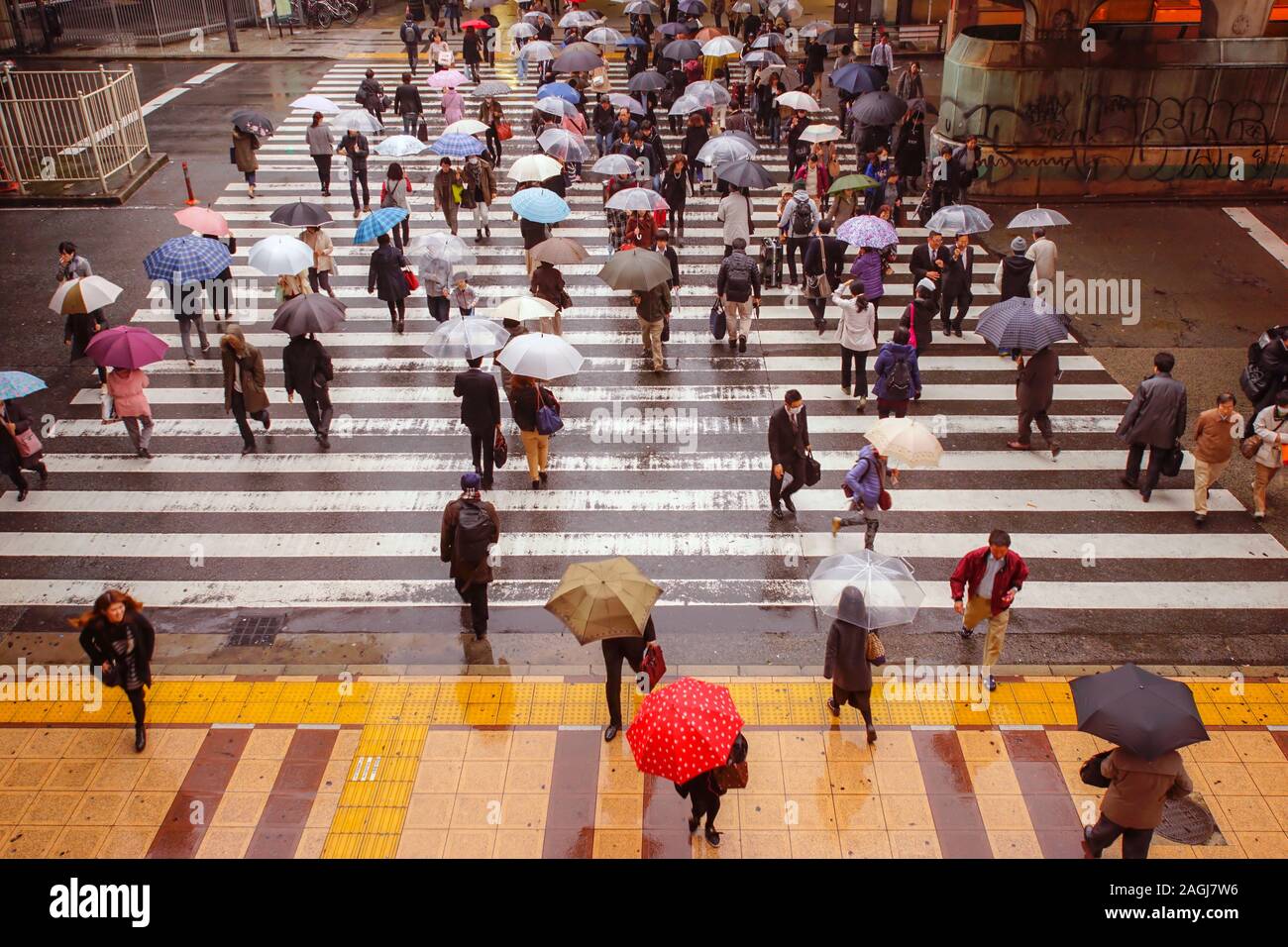 TOKYO, JAPAN - NOVEMBER 25, 2014: People walking under rain in a pedestrian crossing in Tokyo, Japan. Stock Photo