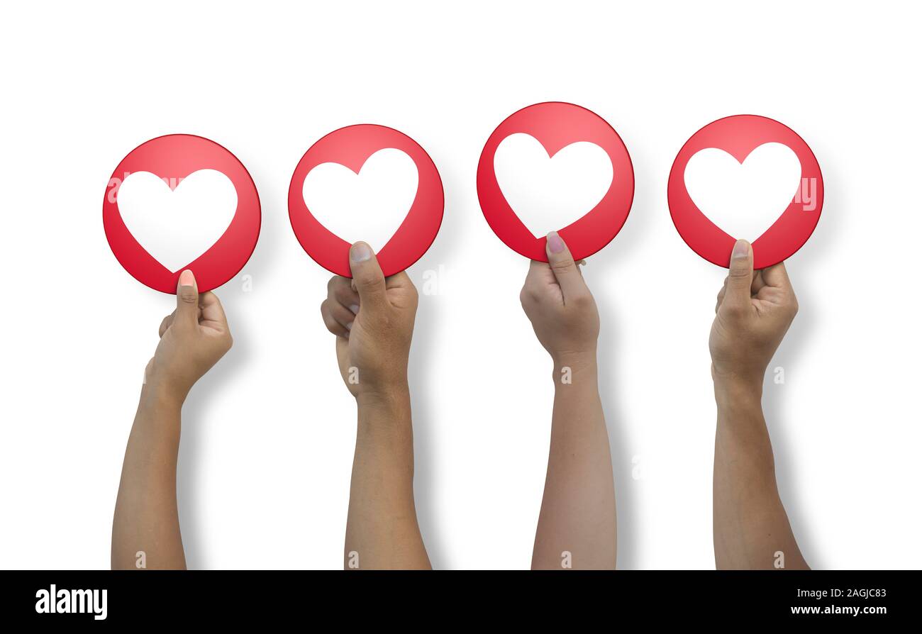 Close up on 4 arms of latin men and women coming out from below holding in hand a round red I LOVE icon on white background Stock Photo