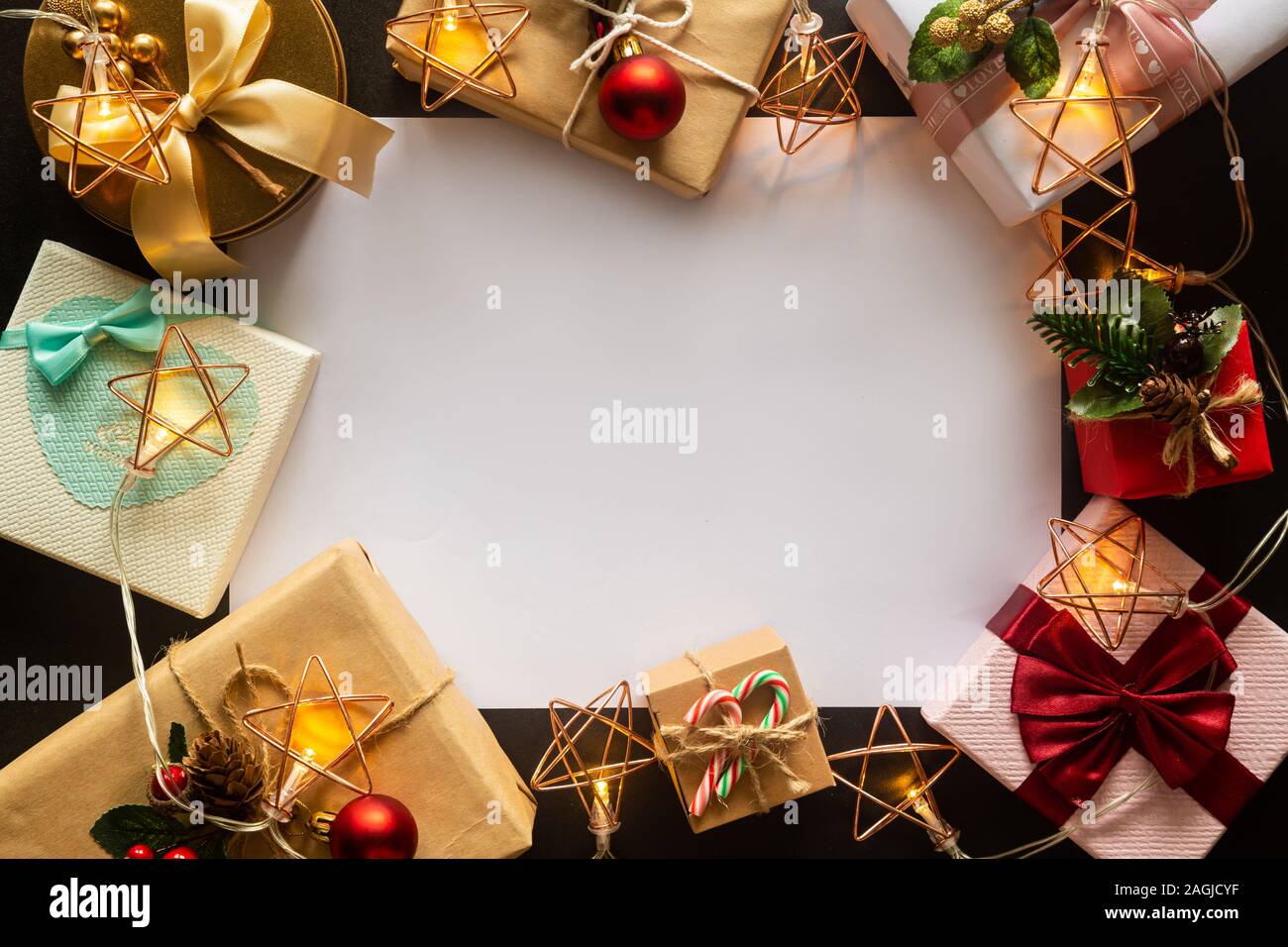 Holiday Christmas card background with festive decoration ball, stars, snowflakes, gift box, pine cones on a black background from Flat lay, top view. Stock Photo