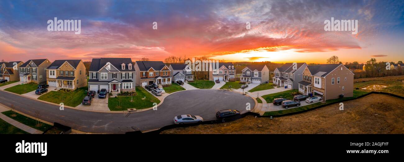 Aerial panorama view of an American suburban cul de sac neighborhood street with single family homes and colorful sunset sky Stock Photo