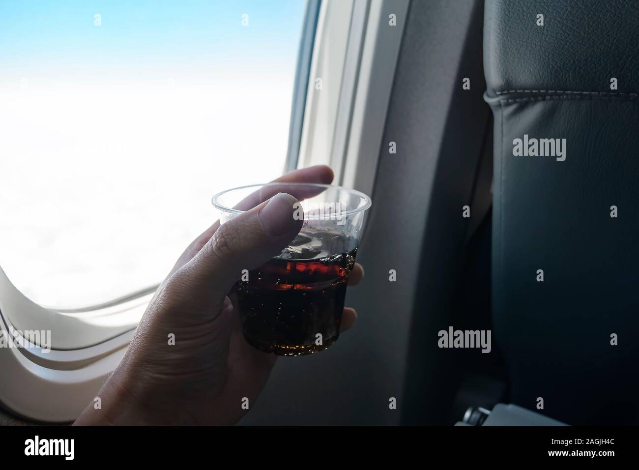Holding a glass of soda on a plane. Drinking soda on a flight Stock