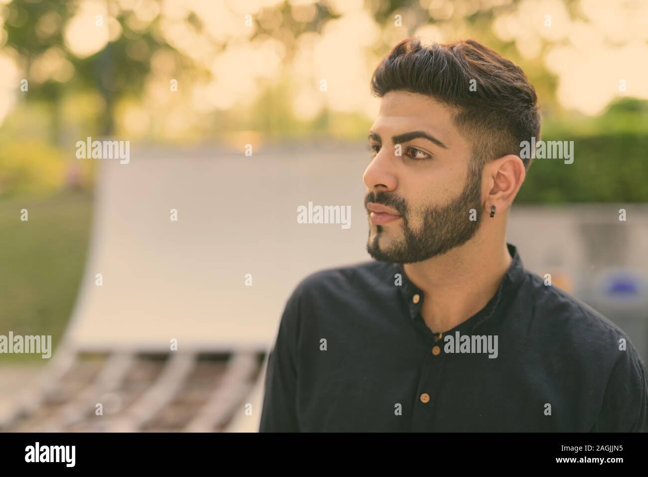 Close Up Of Young Handsome Indian Man Thinking Against Skateboard