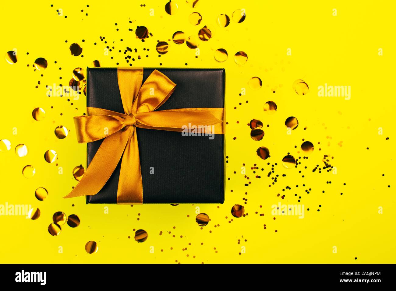 Black gift box with golden bow on yellow background with glitter. Holiday  concept Stock Photo - Alamy