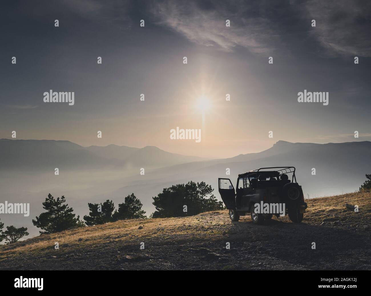 Off road car on top of mountain at sunrise or sunset. Horizontal image for adventure stories Stock Photo