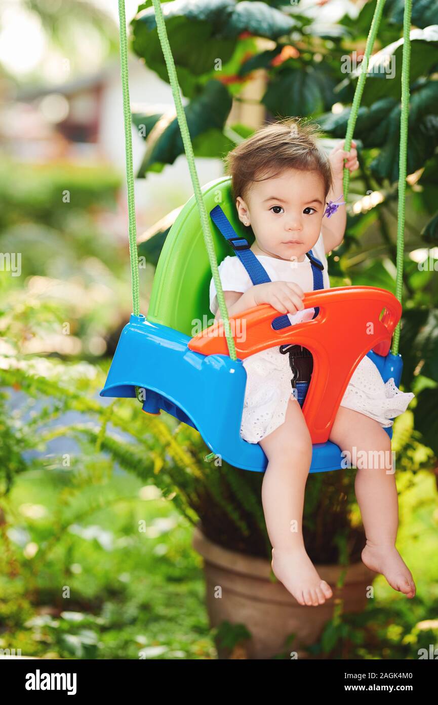 Little cute girl swinging on green park background Stock Photo