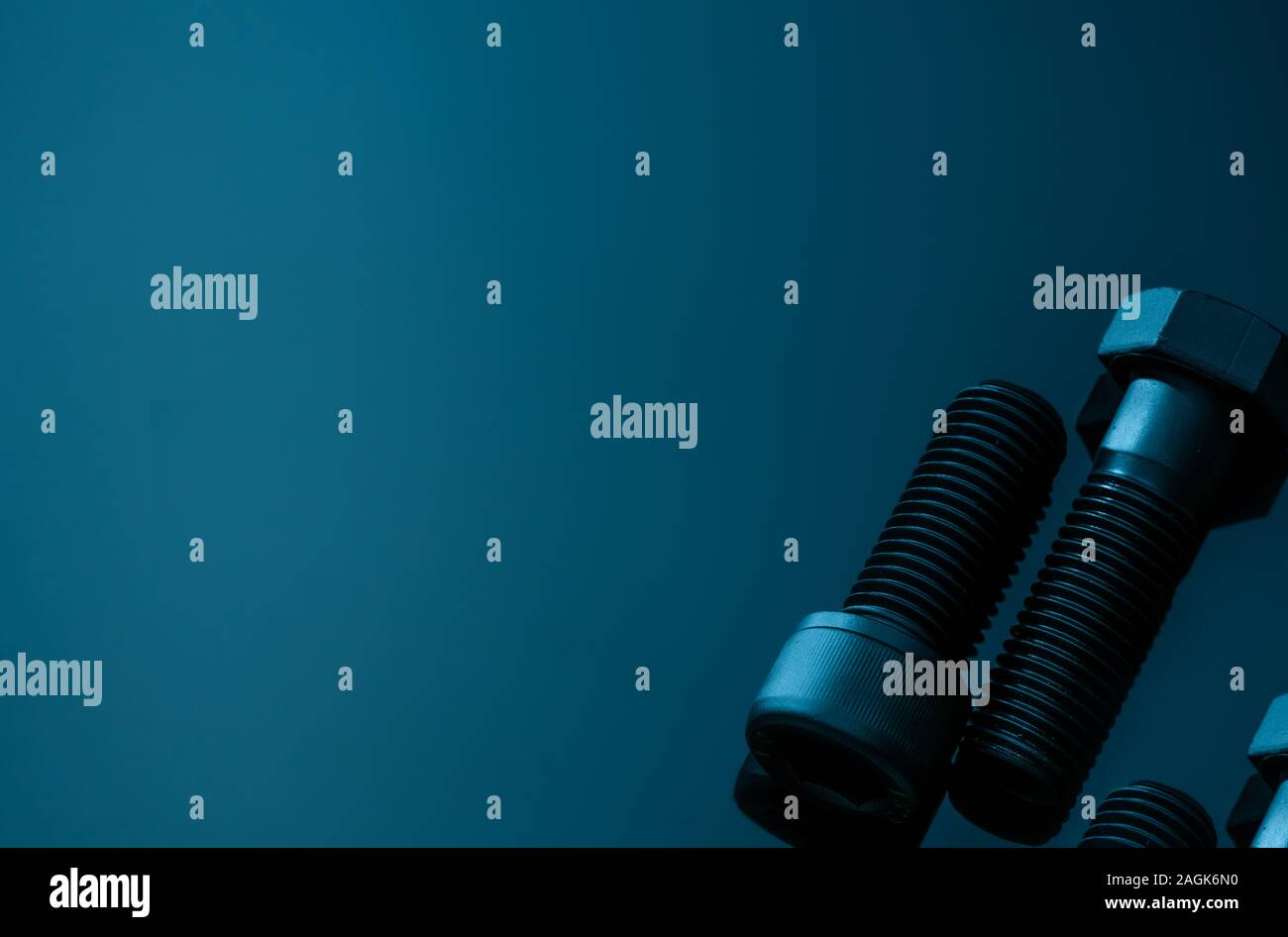 Metal bolts on blue background. Hardware tools. Closeup hex head bolt and socket cap bolt with copy space. Threaded fastener use in automotive Stock Photo
