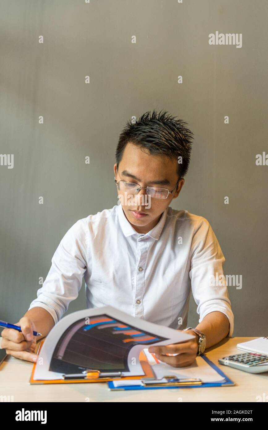 Young businessman wearing glasses focus on analyzing chart documents Stock Photo