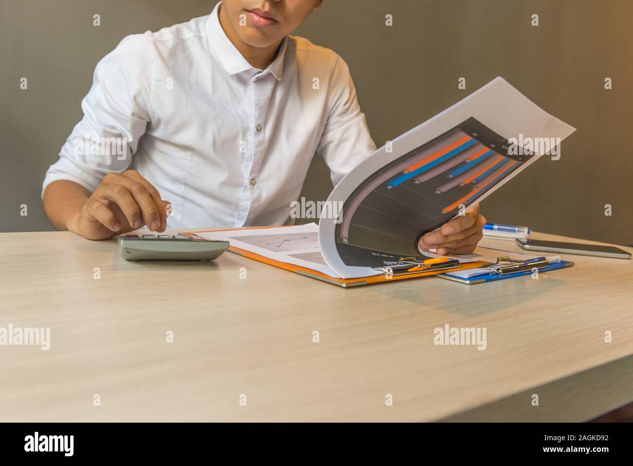 Financial accountant analyzing chart document data on calculator Stock Photo