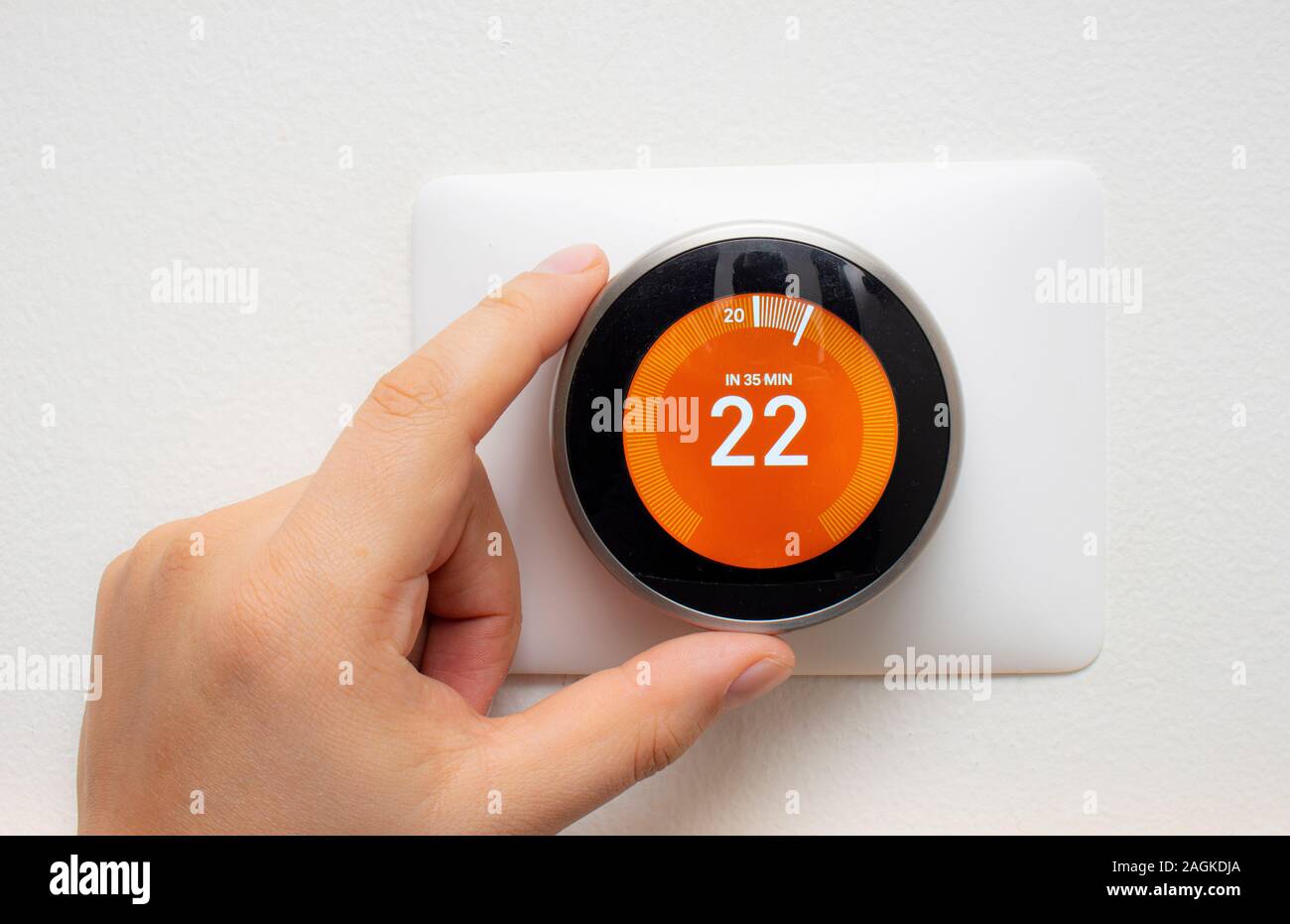 Smart Thermostat with a person warming up the room temperature with a soft shadow Stock Photo