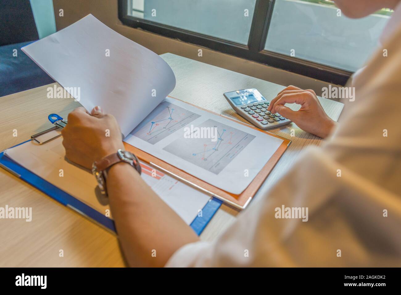 Financial accountant reading sales document and using calculator Stock Photo