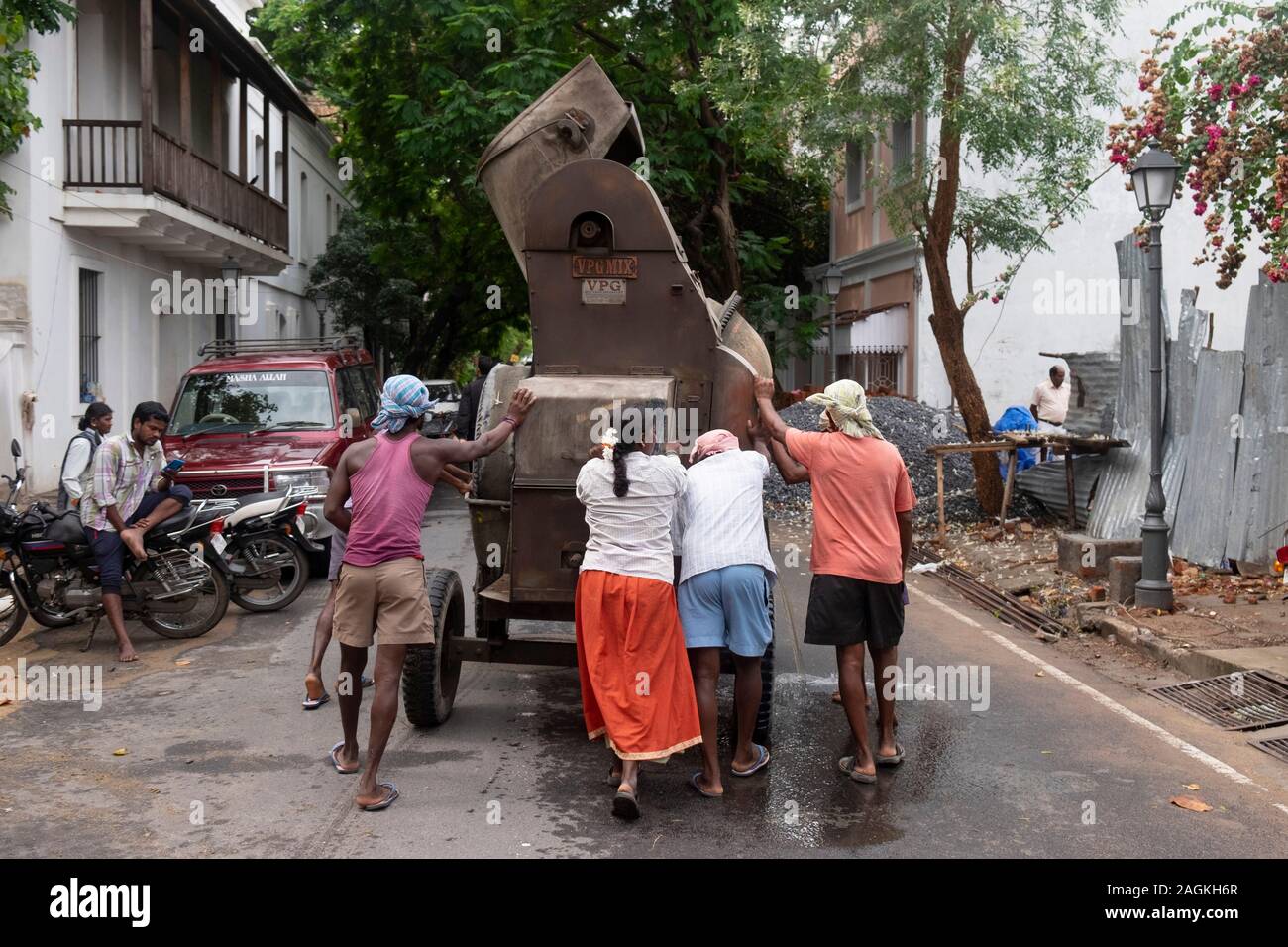 Construction workers pushing a machine in Puducherry, Tamil Nadu, India Stock Photo