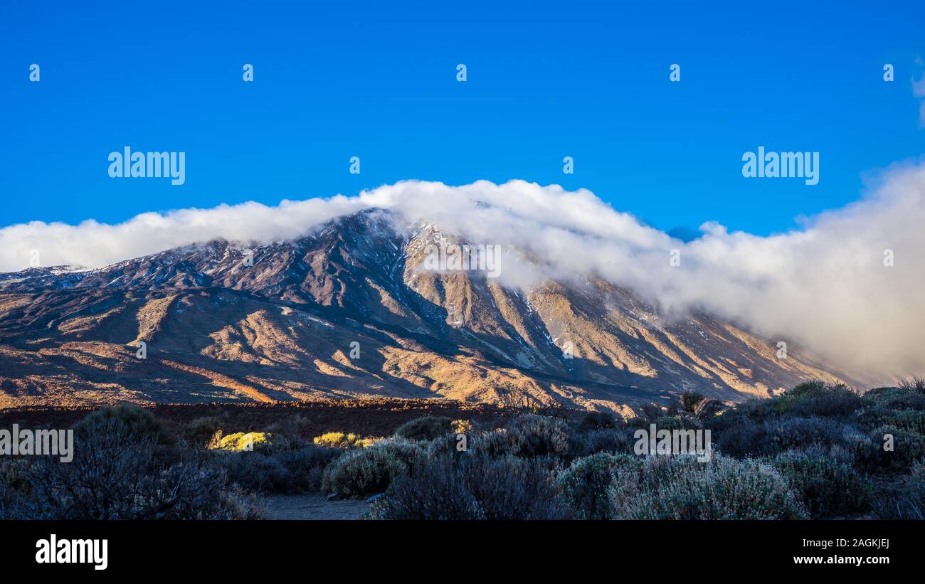 Spain, Tenerife, Volcanic mountain teide with blue sky and covered by fog clouds on sunny day in winter in caldera, a magical nature landscape Stock Photo