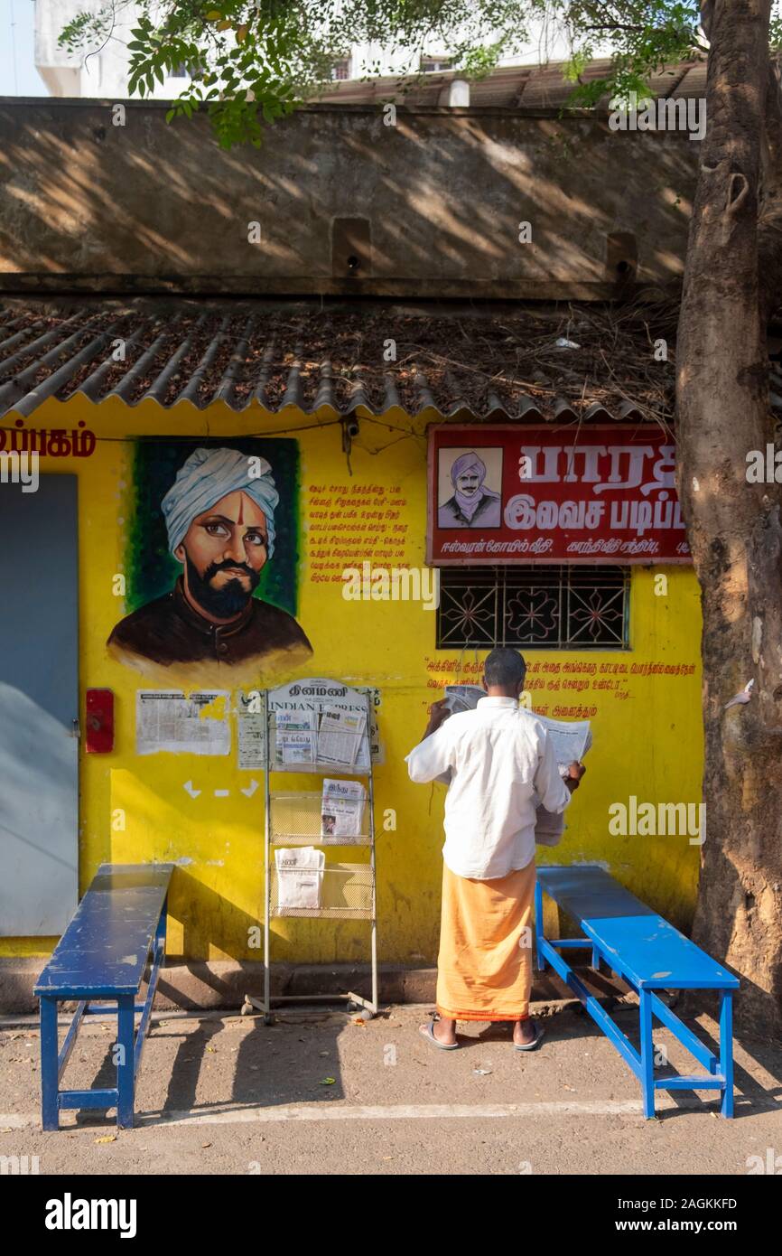 Rear view of man reading newspaper at newspaper stand in Puducherry, Tamil Nadu, India Stock Photo