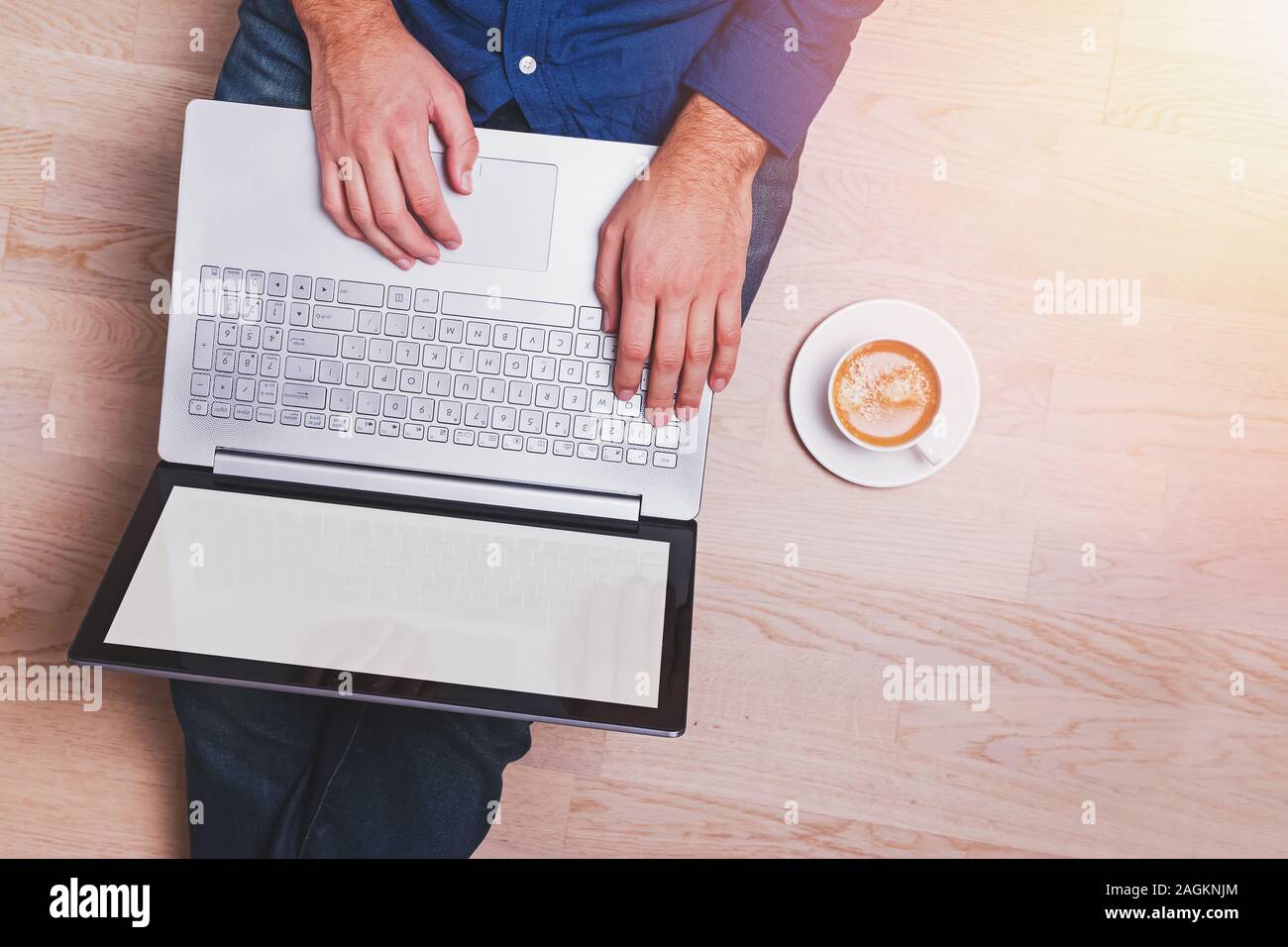 Man sitting on the wooden floor and working on laptop Stock Photo