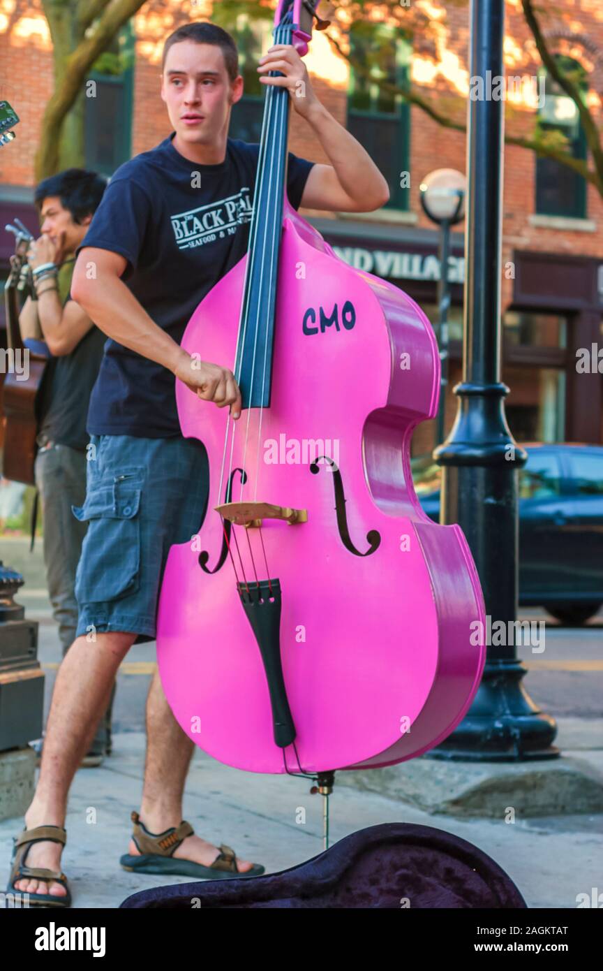 A young musician at a street corner in downtown Ann Arbor playing an acoustic bass. Stock Photo