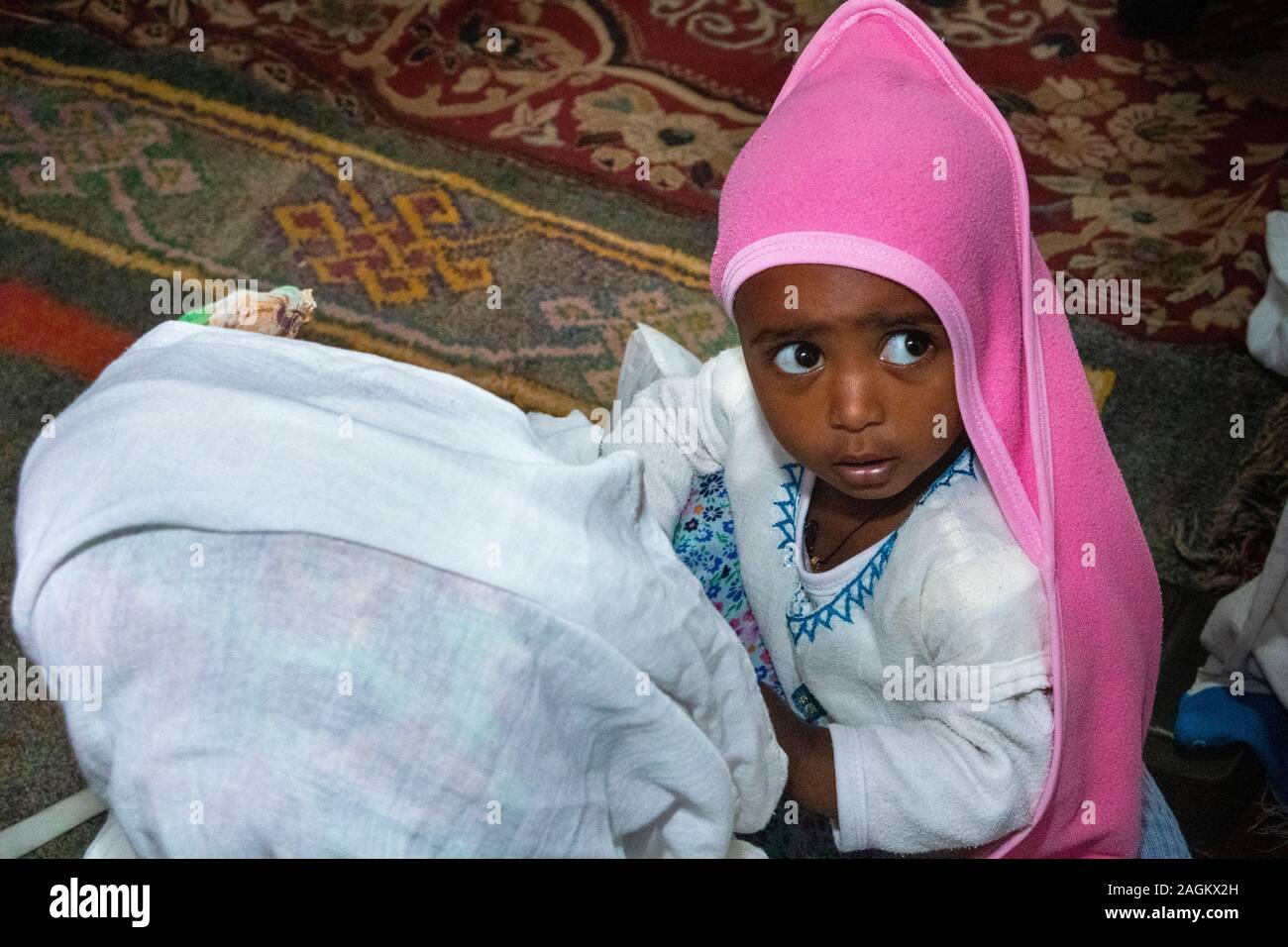 Ethiopia, Amhara Region, Lalibela, Bet Gabriel Rafael, worshipper holding young child in arms during mass Stock Photo