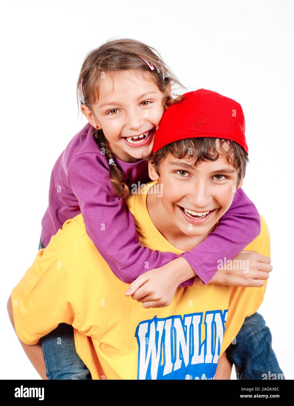 happy teenage boy giving his little sister  piggy back ride - isolated on white Stock Photo