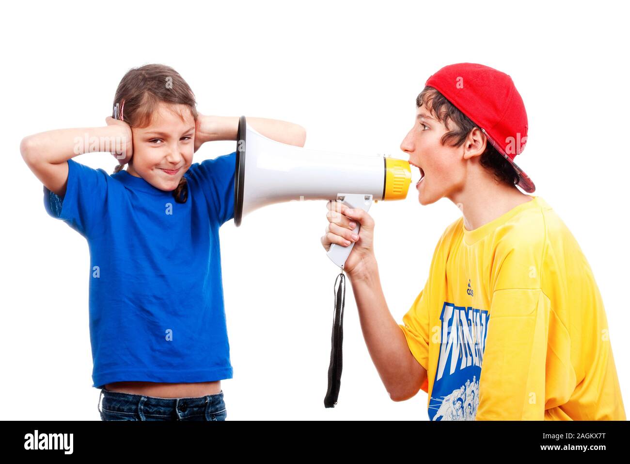 teenage boy yelling through a megaphone to his little sister - isolated on white Stock Photo