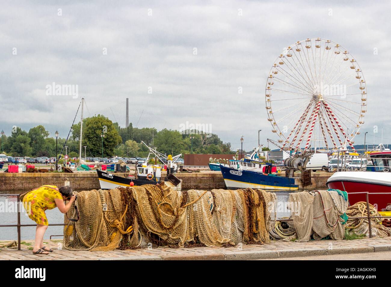HONFLEUR, FRANCE - Aug 15, 2018: Femme photographiant des filets de pêche au port de Honfleur, avec en arrière-plan des bateaux de pêche, une grande-r Stock Photo